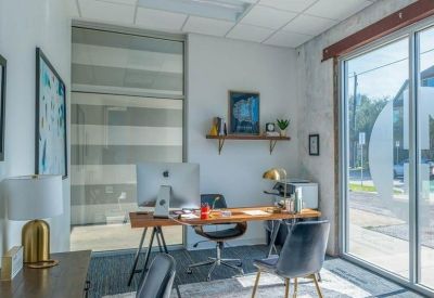 Private office suite with a wooden desk, plush chairs, and large windows.