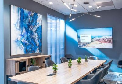 Professional meeting room with a large wooden table, grey chairs, and blue abstract art.