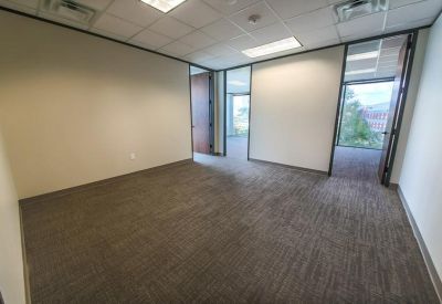 Empty private office suite with grey carpet and two glass door entrances.