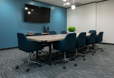 Modern conference room with a long wooden table, blue chairs, and a wall-mounted TV.