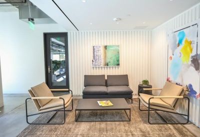 Modern lounge area with grey sofa, neutral armchairs, and abstract wall art.