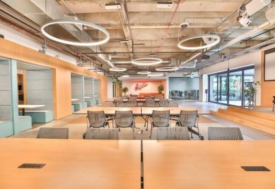 Large multipurpose room with long tables, mesh chairs, and circular pendant lights.