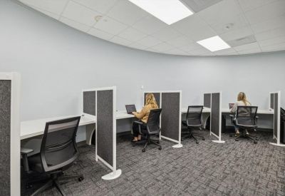 Curved coworking space with white desks and charcoal privacy dividers.