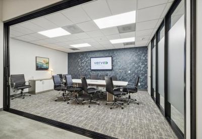 Large glass-walled boardroom featuring a patterned accent wall and modern black chairs.