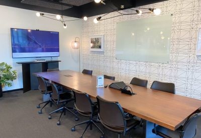 Professional boardroom with large wooden table and wall-mounted screen.