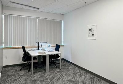 Private window office with two desks and a framed abstract art piece.