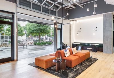 Spacious sunlit lounge area with orange modular seating and views through an open garage door.