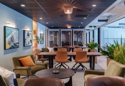 Spacious coworking lounge with mid-century modern furniture, pendant lights, and vibrant wall art.