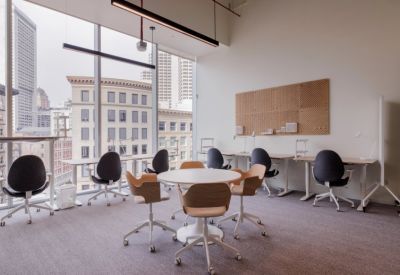 Bright workspace featuring several ergonomic desks and a central round collaboration table.