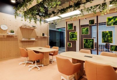 Meeting area with round wooden tables, orange chairs, and a lush hanging plant installation.