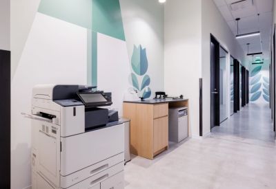 Clean office corridor featuring a printing station and floral wall graphics.