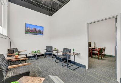 Bright waiting area with contemporary black seating, wooden side tables, and a view into a private office.