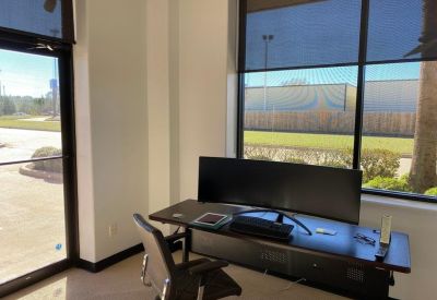 Private office workspace with a wide curved monitor and large window views.