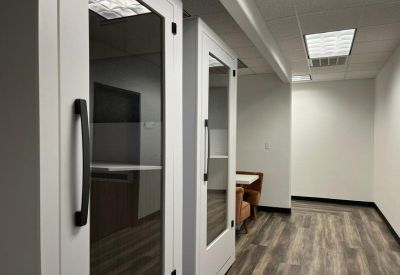 Sleek white privacy phone booths for quiet calls in an office corridor.
