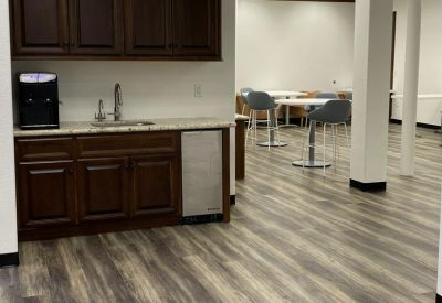 Modern breakroom kitchen with dark wood cabinetry and high-top cafe seating.