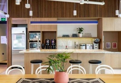 Modern kitchen and breakout area with wooden cabinetry, breakfast bar, and stools.