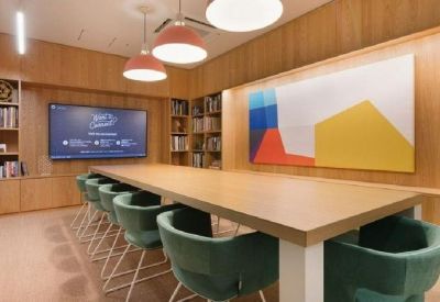 Elegant meeting room with green velvet chairs, wooden paneling, and vibrant abstract art.