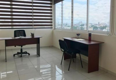 Private office space featuring two wooden desks and expansive city views through large windows.