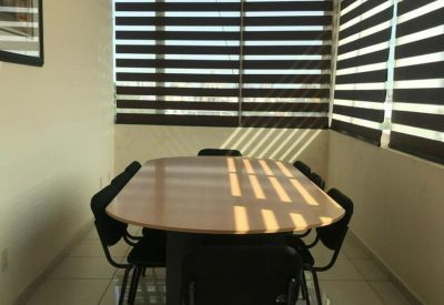 Bright conference room with a large wooden table and horizontal privacy blinds.