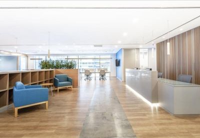 Spacious reception area with a sleek white desk, blue armchairs, and warm wood flooring.