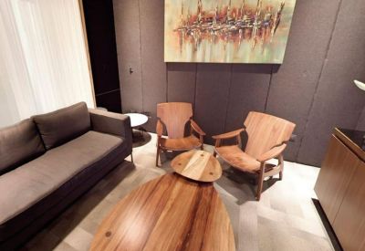 Cozy lounge area with two wooden armchairs and a modern abstract painting.
