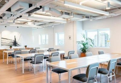 Large open-plan office area with rows of white desks and grey chairs.