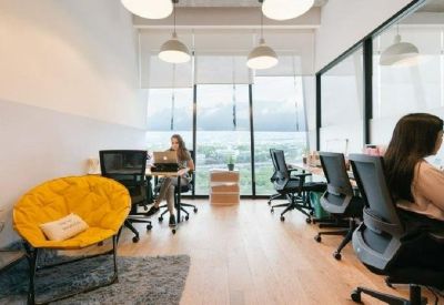Modern office space featuring a bright yellow papasan chair and ergonomic workstations.