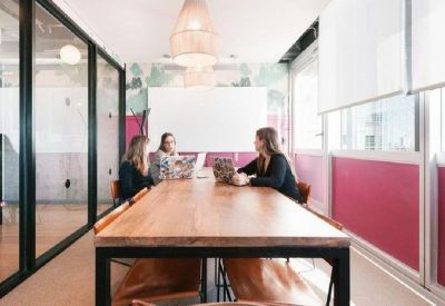 Professional meeting room with a long wooden table and pink accent wall panels.