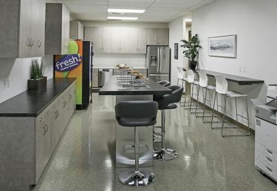 Bright office kitchen and breakroom featuring a high-top island and vending machine.