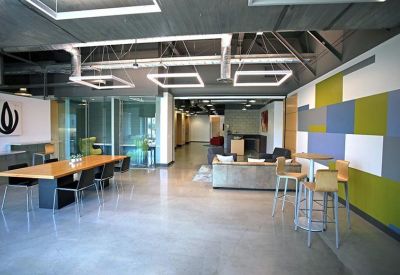 Spacious communal lounge featuring a long wooden table, grey flooring, and a colourful accent wall.