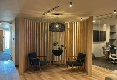 Modern breakout area with blue armchairs and a decorative wood slat partition.