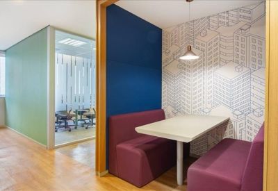 Secluded booth seating with vibrant blue and purple accents and building-themed wallpaper.