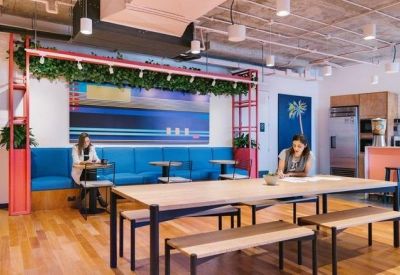 Modern breakout space featuring a long wooden communal table and a vibrant blue booth seat.