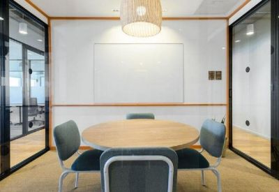 Small meeting room with a round wooden table, four blue chairs, and a white board.