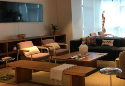 Lounge area with mid-century modern armchairs, a wood coffee table, and a wall-mounted TV.