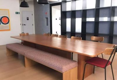 Meeting room with a long wood table, bench seating, and grid shelving.