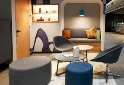 Modern lounge area with gray armchairs and blue ottoman.