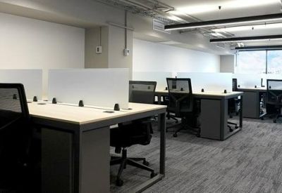 Open-plan office space with rows of desks and ergonomic chairs.
