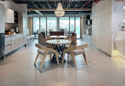 Breakout area with round café tables and contemporary chairs near a kitchen.