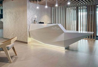 Angled white geometric reception desk with pendant lighting.