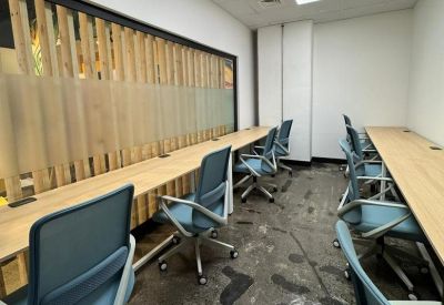 Long wooden coworking desk with blue ergonomic chairs and slat wall accents.