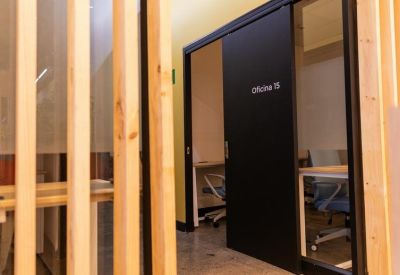 Modern private office with a black sliding door and wooden slat partitions.