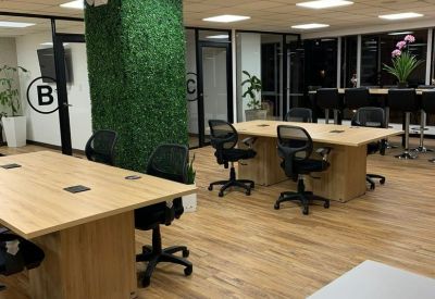 Bright workspace featuring wooden desks and a vibrant green plant-covered accent wall.