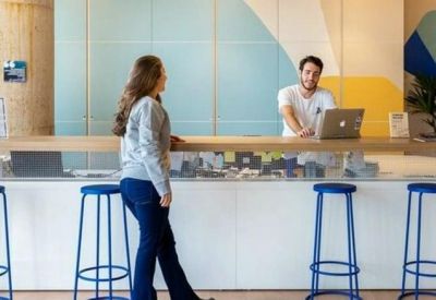 Bright reception desk with blue bar stools and a minimalist wall mural.