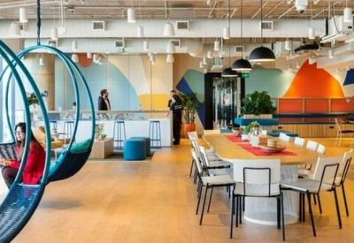 Large open-plan coworking space featuring hanging pod chairs and a long wooden table.