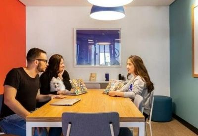 Small meeting room with a wooden table and vibrant red and blue walls.