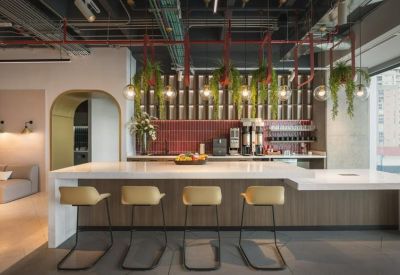 Communal kitchen and break area featuring a large marble island, leather bar stools, and hanging plants.