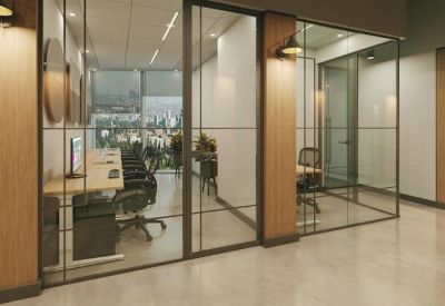 Row of glass-fronted private office booths with integrated lighting and wooden pillars.