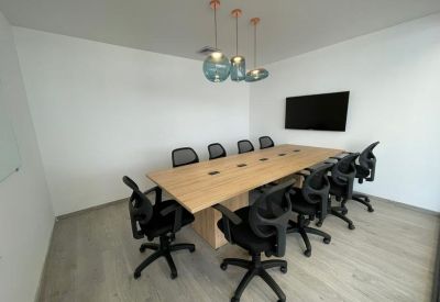 Spacious boardroom featuring a light wood table and ergonomic black mesh chairs.