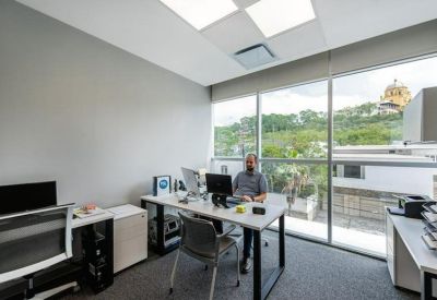 Private glass-walled office with a desk and panoramic city views.